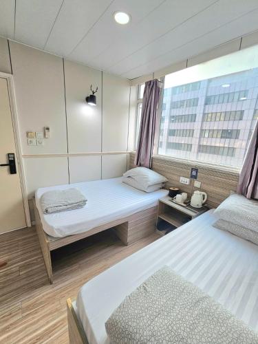 a hotel room with two beds and a window at K & B Hostel in Hong Kong