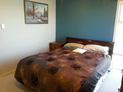 a bedroom with a bed with a comforter on it at Million Dollar View in Wellington