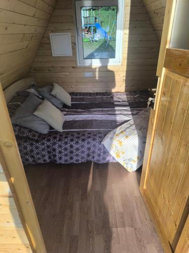 a small bed in a wooden room with a window at Hiška Nika in Malečnik