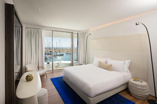 a bedroom with a white bed and a large window at The YACHT - By Fattal Limited Edition in Herzliya B