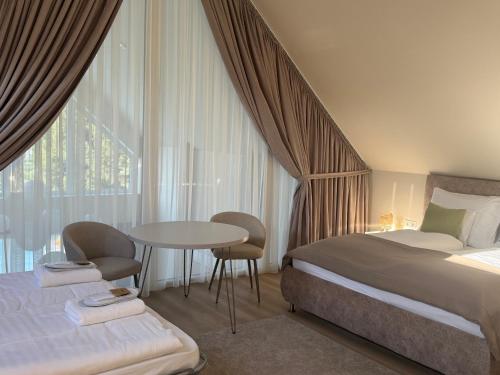 a bedroom with a bed and a table and a window at Kálló Villa in Nagykálló