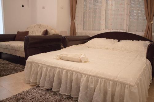 a bedroom with a large white bed and a couch at Apartments Matija&scaron;ević in Nik&scaron;ić