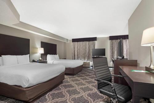 a hotel room with two beds and a desk at Quality Suites Pineville - Charlotte in Charlotte