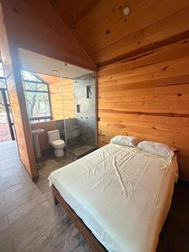 a bedroom with a large bed in a wooden cabin at azomalli cabañas in Bernal