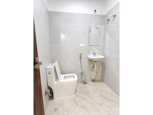 a white bathroom with a toilet and a sink at HOTEL MEDHYA GRAND Near Goḏawalia Chauraha - 200 Meter From Baba Vishwanath Temple & Ganga Arti Ghat ! Wi-Fi #Lift #Hygiene & Spacious Room - BEST HOTEL IN VARANASI in Varanasi