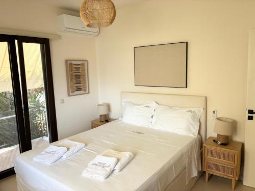 a bedroom with a white bed with towels on it at CasaSmaragdi in Perdika