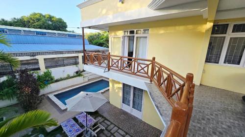 a balcony of a house with a pool and an umbrella at Logement des palmiers in Flic-en-Flac