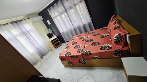 a bedroom with a bed with a red comforter with a spider pattern at Logement des palmiers in Flic-en-Flac