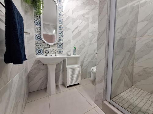 a white bathroom with a sink and a shower at The Wave House on the Beach in Port Alfred