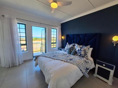 a bedroom with a large bed with a blue wall at The Wave House on the Beach in Port Alfred
