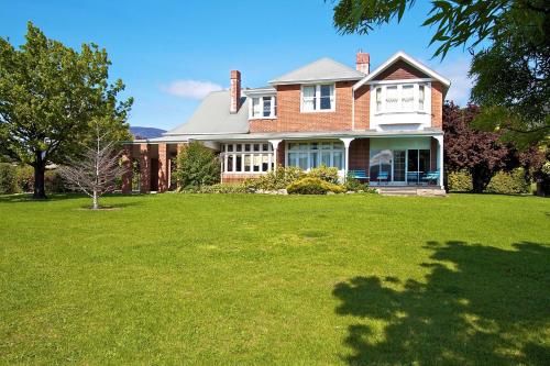 a large brick house with a lawn in front of it at Riverfront Motel & Restaurant in Hobart