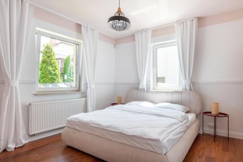 a white bedroom with a bed and two windows at Willa Latarnik - doskonała lokalizacja, blisko atrakcji, 15min do plaży in Łeba