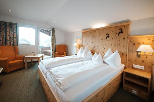 a bedroom with a large white bed with a wooden headboard at Schi- und Wanderhotel Berghof in Bad Kleinkirchheim