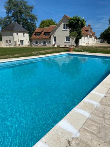 a blue swimming pool in front of a house at Le clos du cèdre in Cellettes