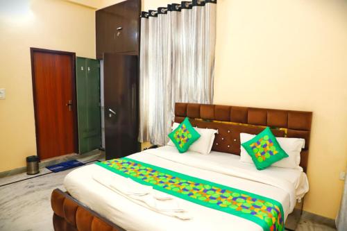 a bedroom with a large bed with green and yellow pillows at Hotel Relax in Jaipur