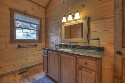 a bathroom with a sink and a mirror at Squirrels Hideaway Fire Pit MTN Views in Copperhill