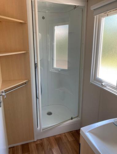 a glass shower in a bathroom with a window at Mobile home climatisé 4 personnes proche Europapark in Vogelgrun