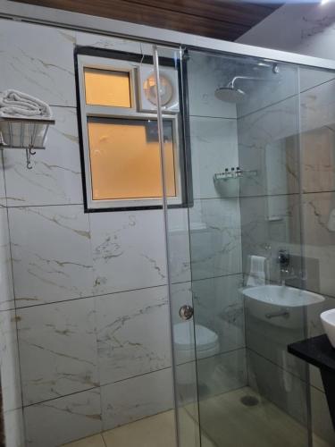 a bathroom with a glass shower with a sink at Platinum Arc in Jaipur