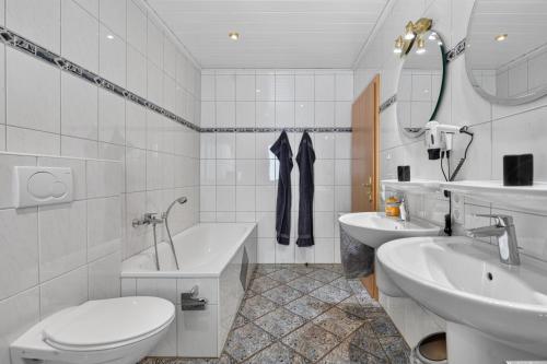 a bathroom with two sinks and a toilet and a tub at Suite Stadtgrün in Papenburg