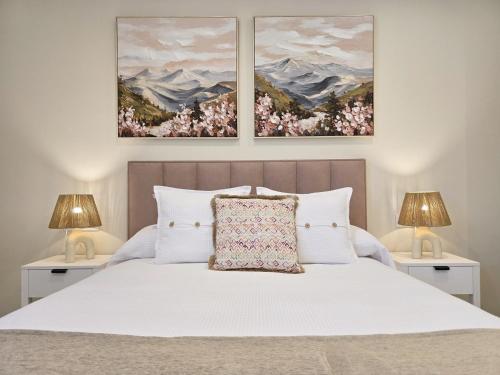 a bedroom with a white bed with two lamps at LURDE Apartamentos Rurales in El Cerezal