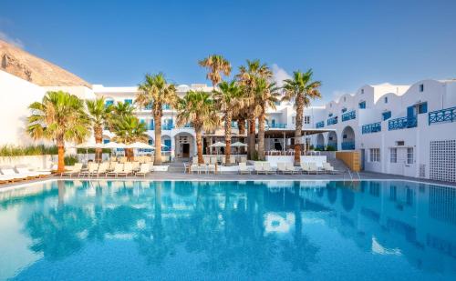 a swimming pool in front of a hotel with palm trees at Kamari Beach Hotel in Kamari