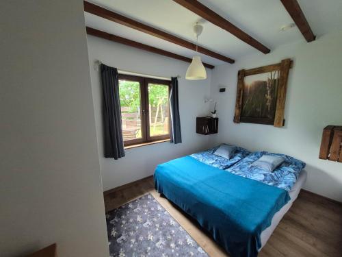 a bedroom with a blue bed and a window at Chatki u Patki in Łebieniec