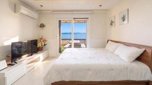 a white bedroom with a large bed and a television at Taean Tteulapbada Pension in Taean