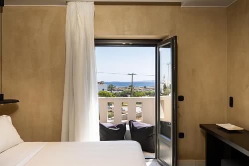 a bedroom with a bed and a balcony with a view at Melidron Hotel Suites Villas in Agios Prokopios
