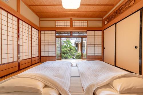 a japanese bedroom with two beds and a window at Villa Taniguchi in Takayama