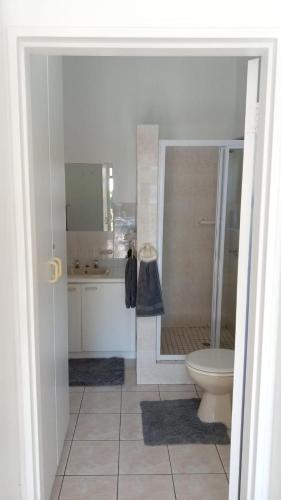 a white bathroom with a toilet and a shower at La Casita House in St Francis Bay