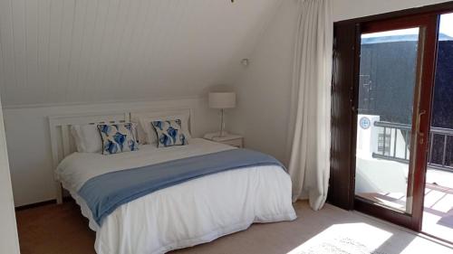 a white bedroom with a bed and a window at La Casita House in St Francis Bay