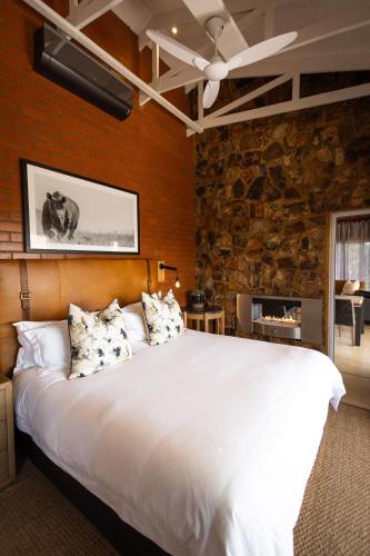 a bedroom with a large white bed and a stone wall at Rockfig Lodge Madikwe in Madikwe Game Reserve