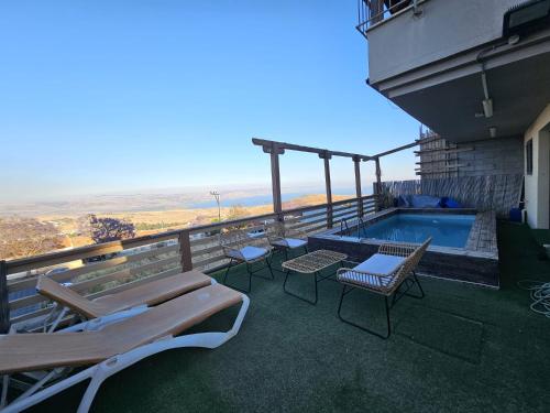 a balcony with a swimming pool and tables and chairs at Kinneret view with pool in Safed