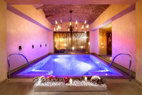 a swimming pool in a room with a chandelier at Château Monfort - Relais & Châteaux in Milan