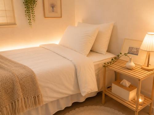 a bedroom with a white bed and a table with a lamp at BLAU Korean Local Experience Stay in Gyeongju