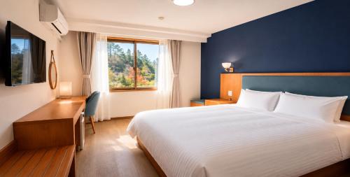 a bedroom with a bed and a desk and a window at Fujinomori Hotel in Fujikawaguchiko