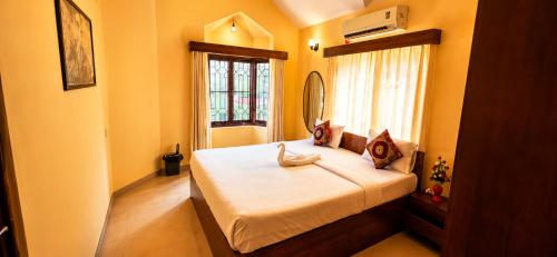 a bedroom with a bed with a mirror and a window at Asif 3 bedroom luxury villa with swimming pool and kitchen in Nagoa-Bardez