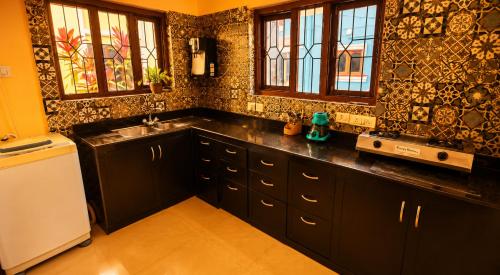 a kitchen with black cabinets and a white refrigerator at Asif 3 bedroom luxury villa with swimming pool and kitchen in Nagoa-Bardez