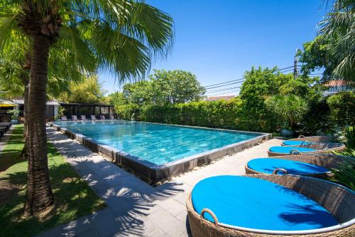 a swimming pool with chairs and a palm tree at Thanh Binh Riverside Hoi An in Hoi An