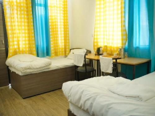 a room with two beds and a desk and a table at The Elite Ambience Hotel in Greater Noida
