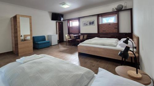 a bedroom with two beds and a chair and a table at Penzion Rondo in Bystřice pod Hostýnem