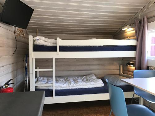 two bunk beds in a room with a table and chairs at Beverøya Hytteutleie og Camping in Bø