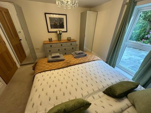 a bedroom with a bed with a dresser and a window at Woody Nook Annexe in Pavenham