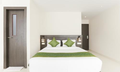 a bedroom with a large white bed with green pillows at Hotel Sunrise Luxury Stays in Chikmagalūr