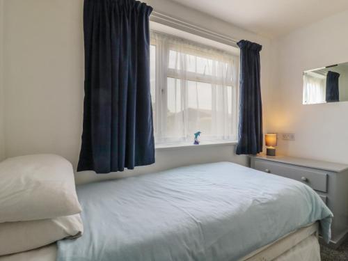 a bedroom with a bed with blue curtains and a window at 38 St Margarets in Dover