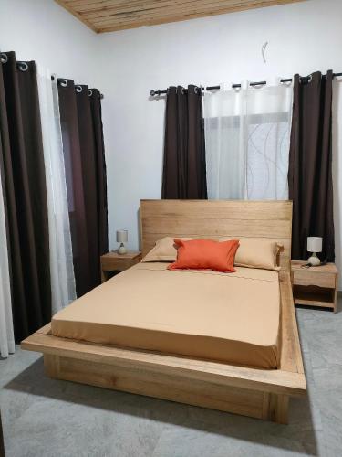 a bedroom with a wooden bed with a red pillow at Residence Meva Soa Majunga in Amborovy