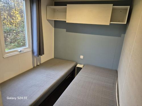 two beds in a small room with a window at Chalet te huur op het 'Eiland' Camping de Kleine Wielen Leeuwarden in Leeuwarden