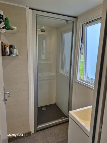a shower with a glass door in a bathroom at Chalet te huur op het 'Eiland' Camping de Kleine Wielen Leeuwarden in Leeuwarden
