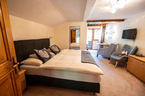 a bedroom with a large bed and a living room at Pension Hartenfels in Lech am Arlberg