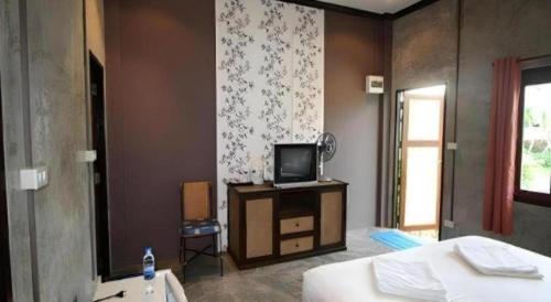 a bedroom with a bed and a television on a dresser at Pilton Resort in Ban Huai Yang